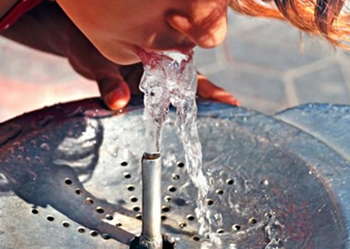An image of a person drinking water from a fountain