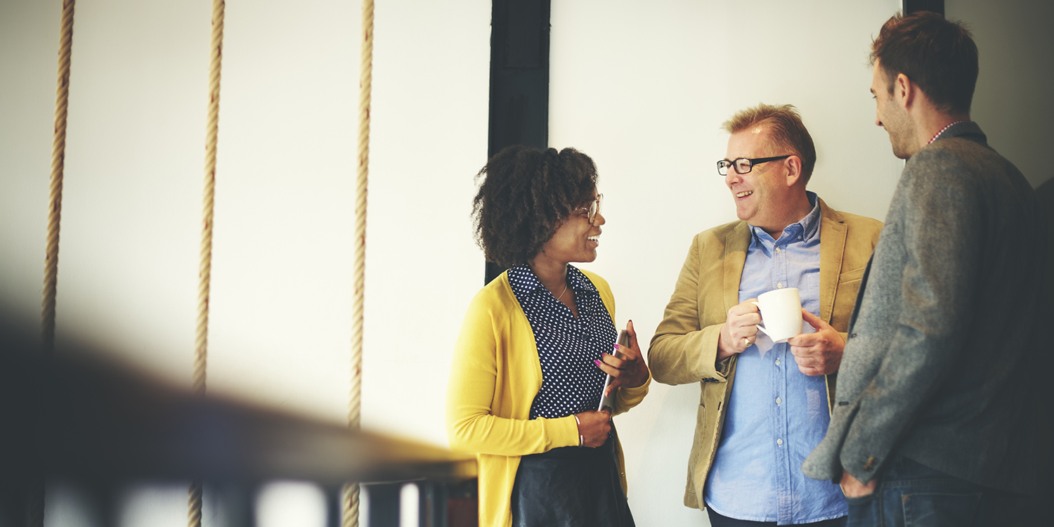 An image of three people networking, one man is drinking coffee