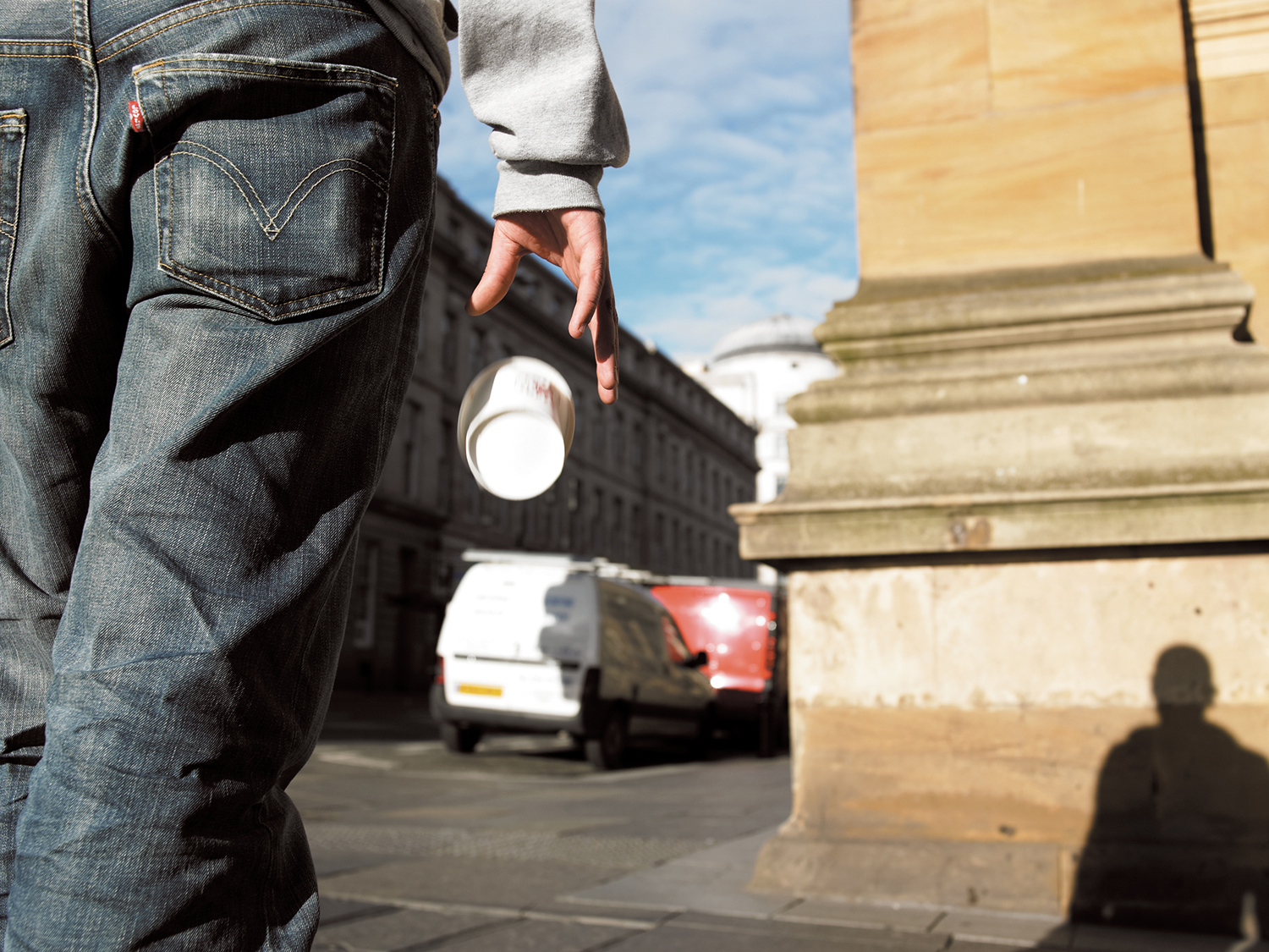 An image of a man walking with a disposable coffee cup in his hand