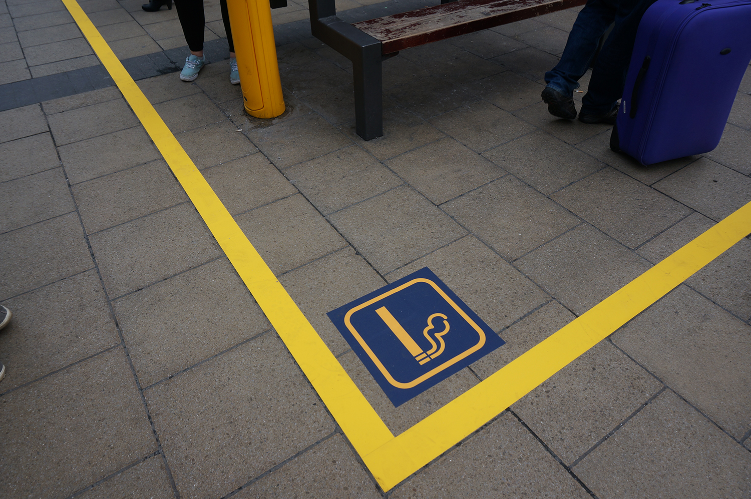 An image of a smoking zone defined by yellow tape and marked with an image of a cigarette 