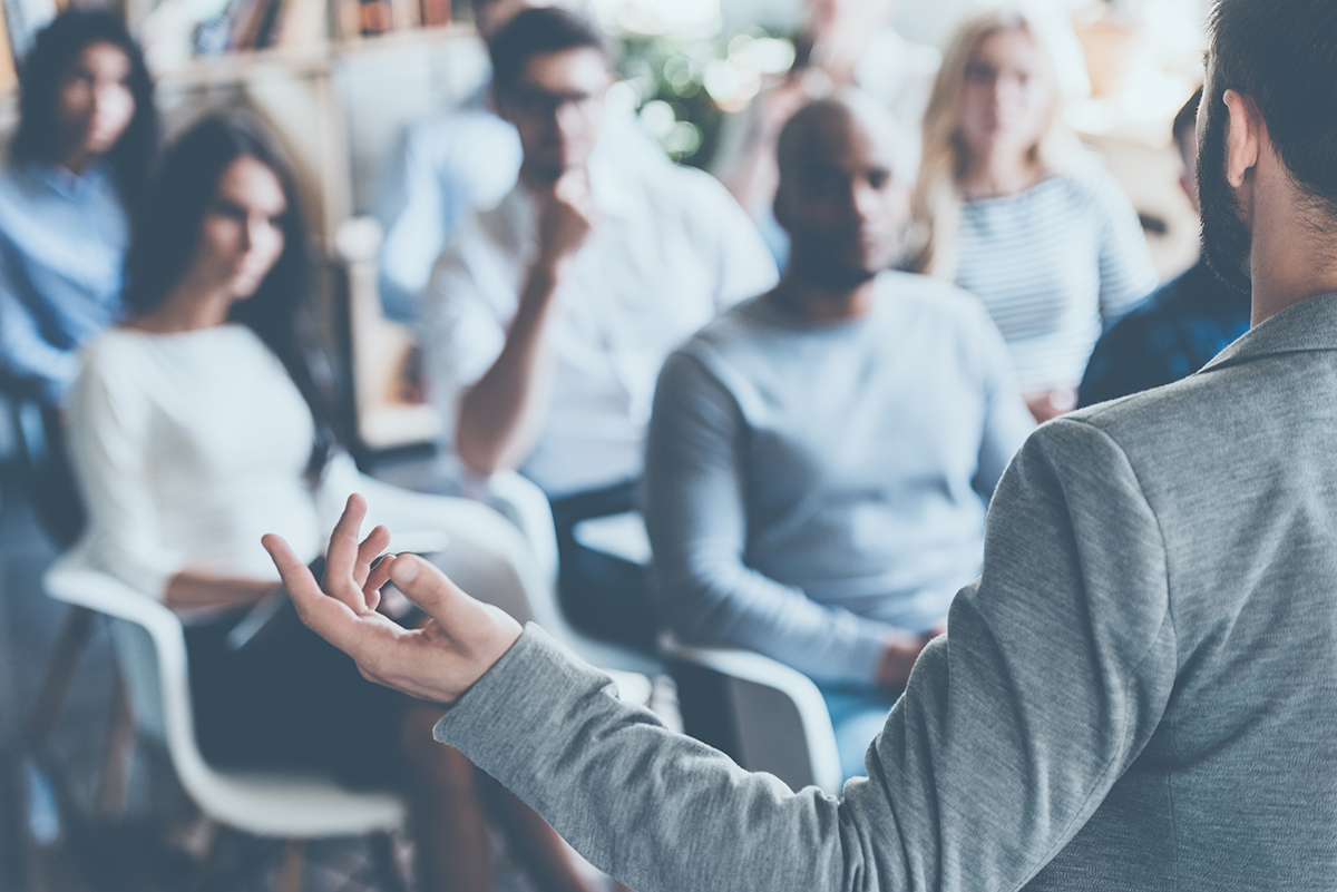 An image of a lecturer at the front of an engaged crowd