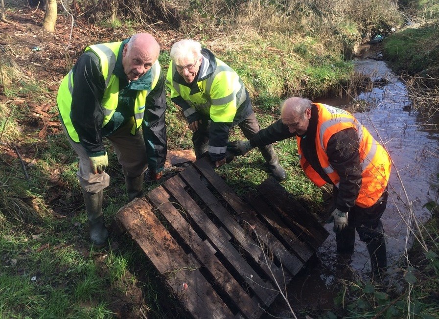 An image of three people clearing a river