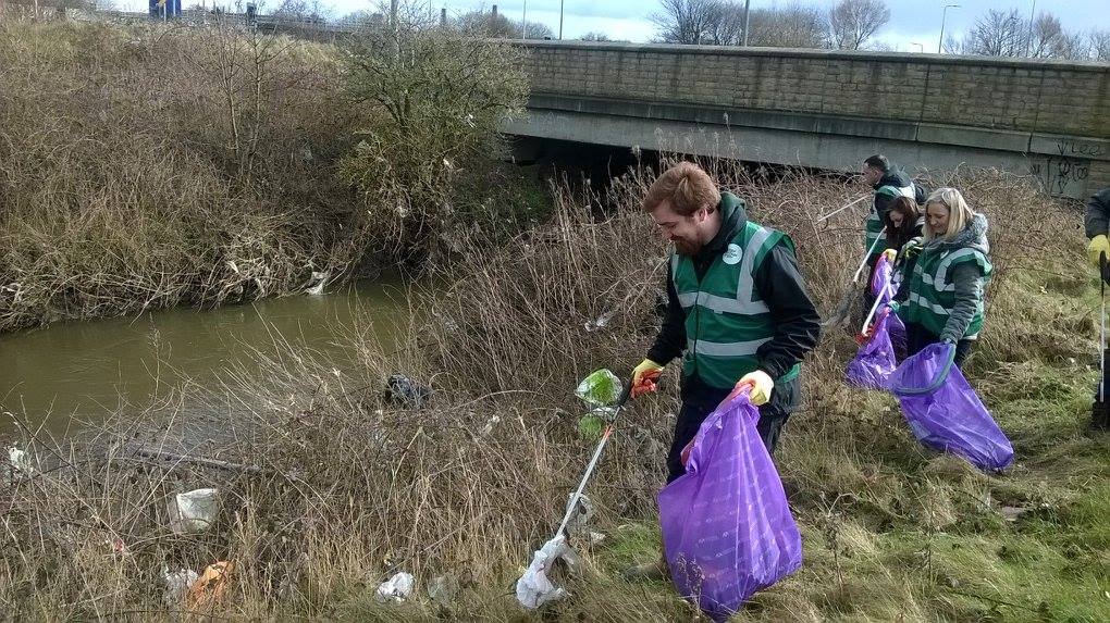 An image of two people by the waterside collecting litter