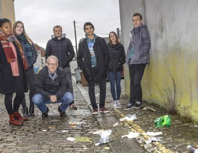 An image of university students standing outside surrounded by litter