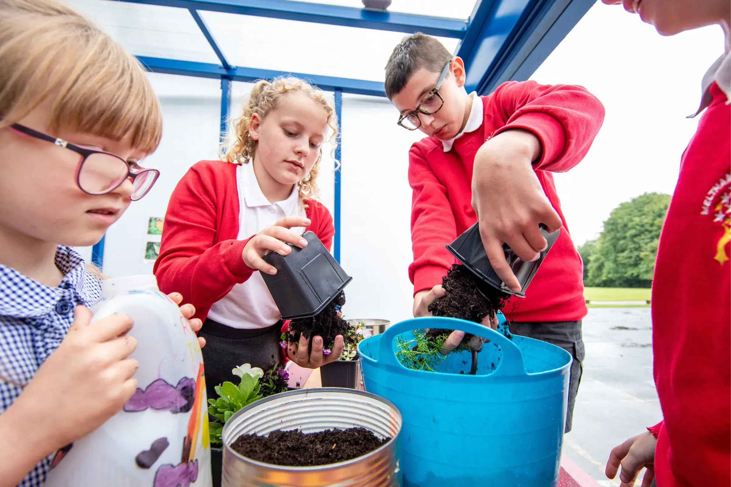 School children planting flowers in pots 