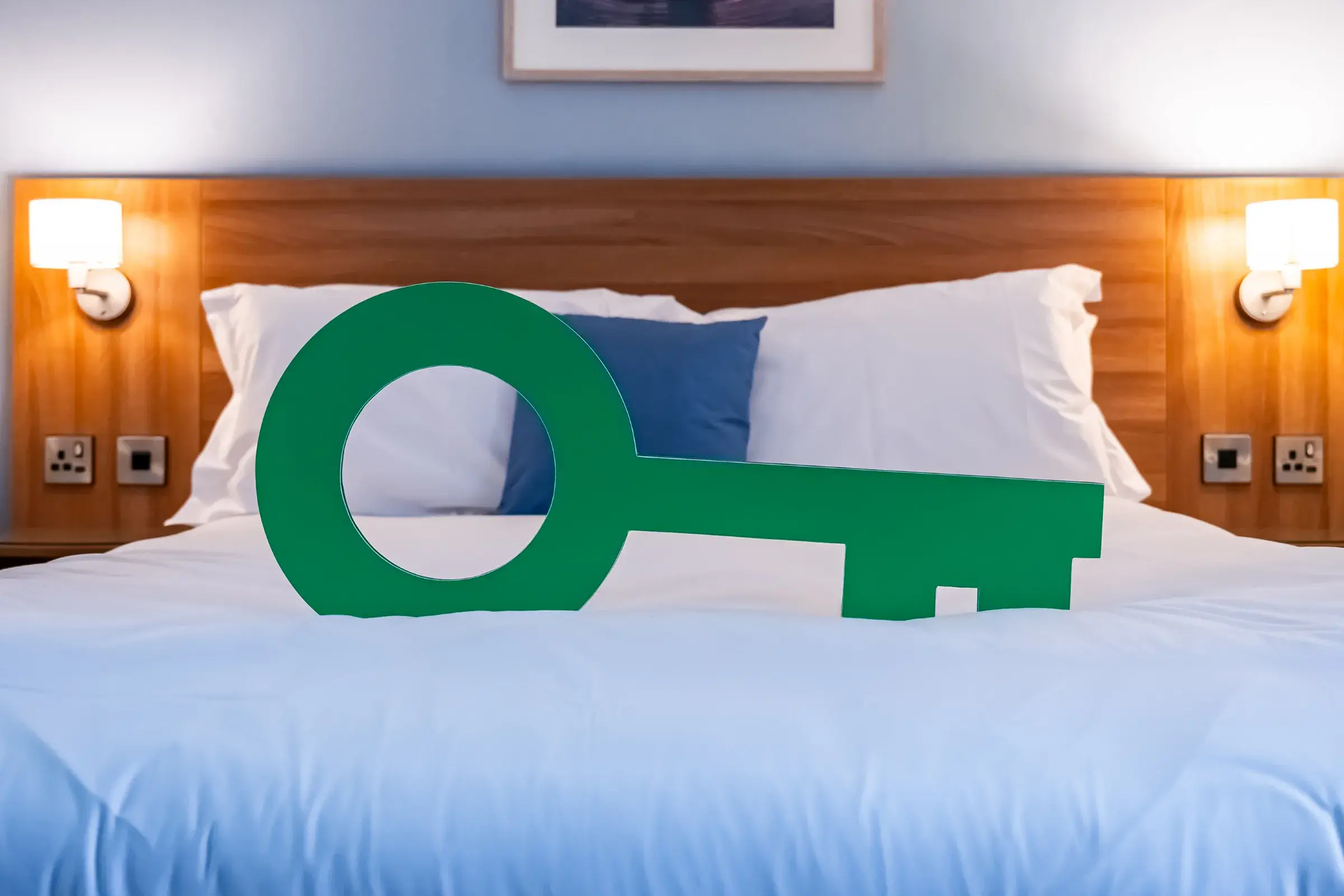 Giant Green Key resting a white hotel bed
