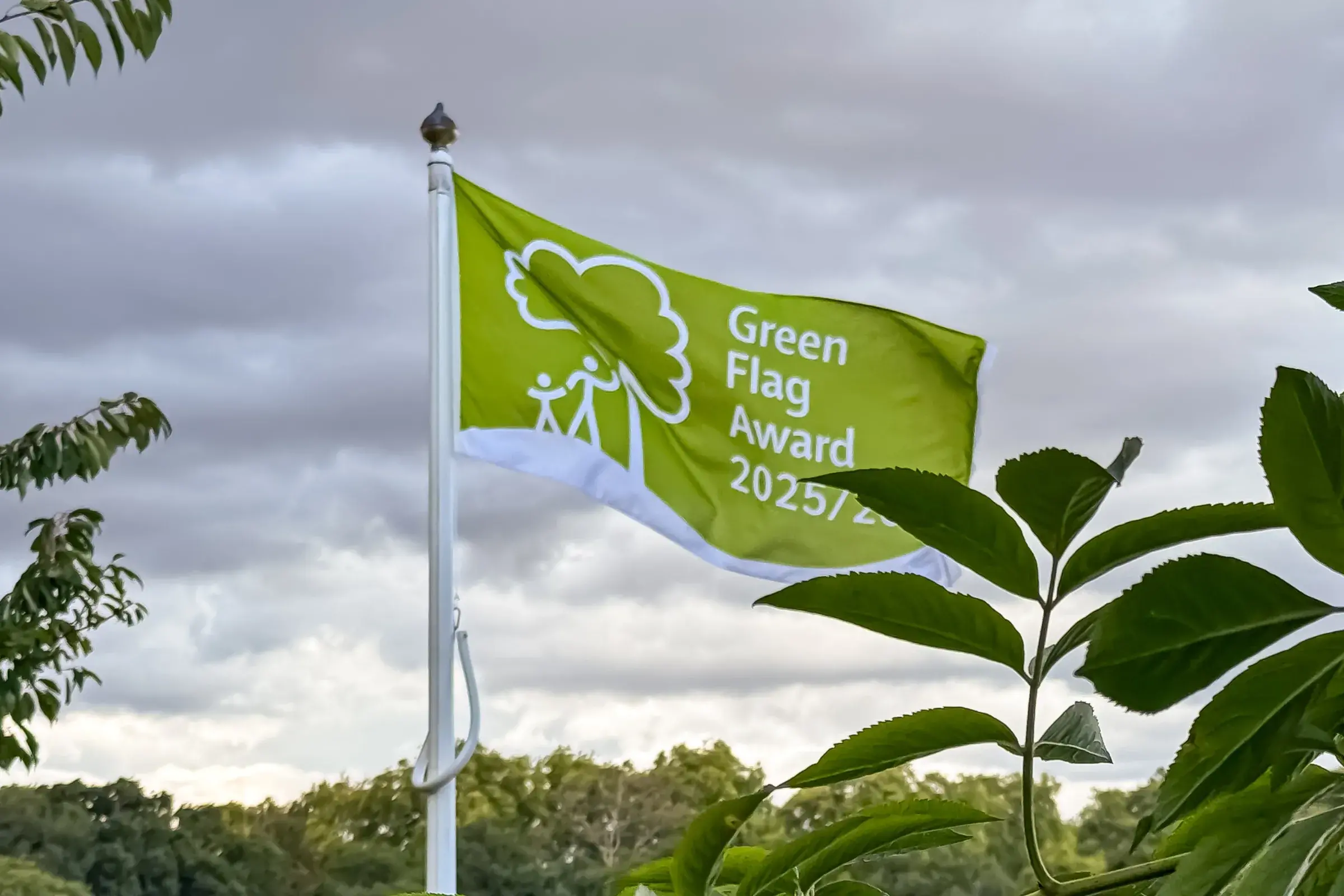 Green Flag Award flag flying behind foliage in an awarded park