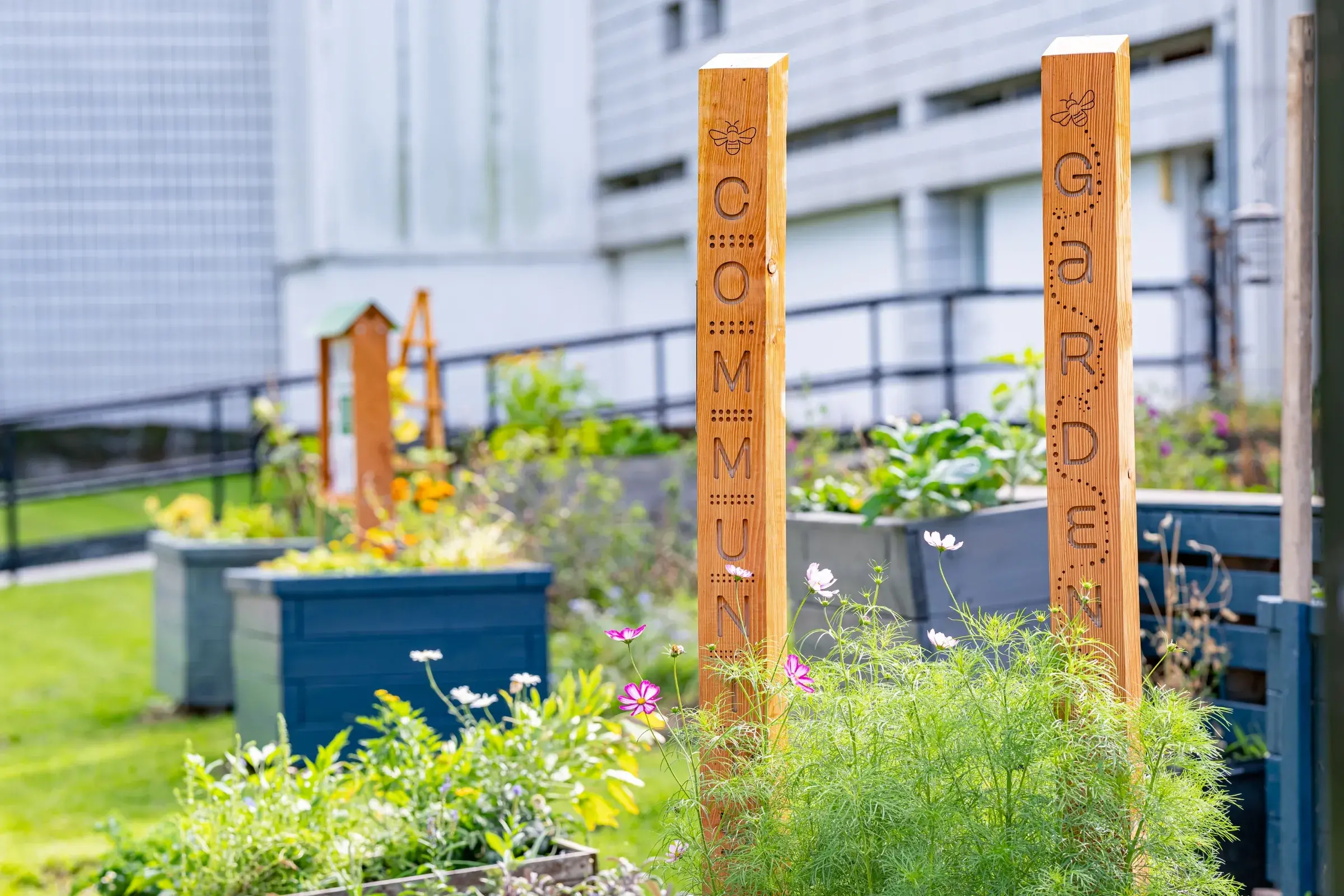 Wooden posts with the words community garden surrounded by flowers